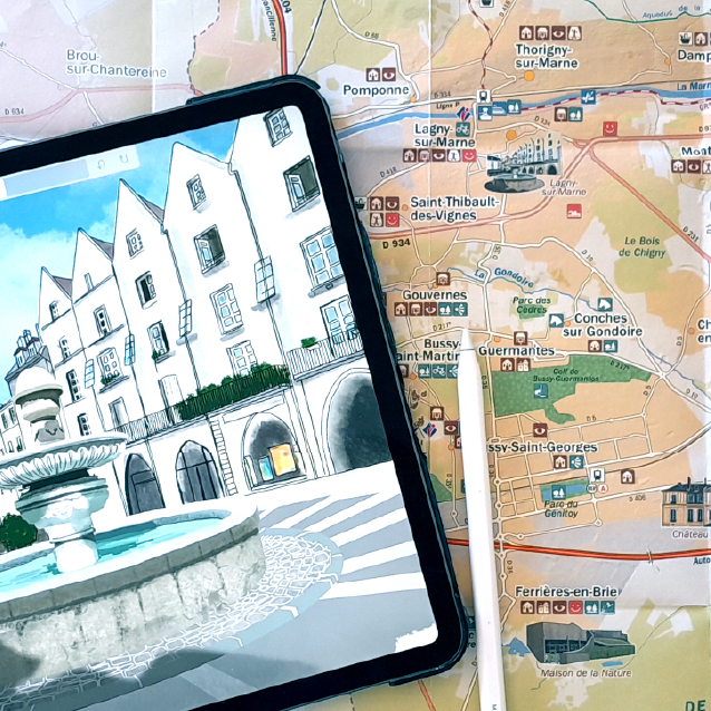 Carte illustrée d’un site touristique. La photo montre une tablette sur laquelle il y a le zoom d'une des illustrations de la carte d'arrière-plan. L'illustration est celle de la place d'un joli village et de sa fontaine centrale.