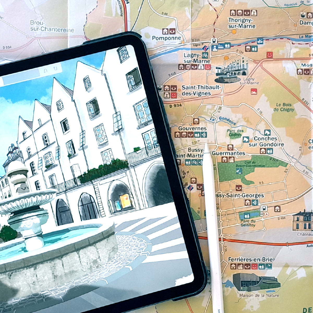Carte illustrée d’un site touristique. La photo montre une tablette sur laquelle il y a le zoom d'une des illustrations de la carte d'arrière-plan. L'illustration est celle de la place d'un joli village et de sa fontaine centrale.